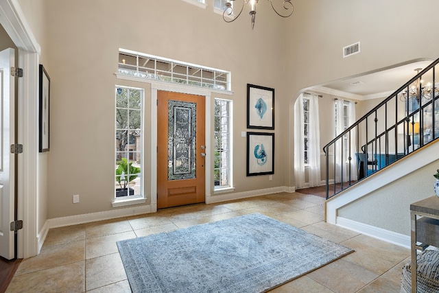 tiled foyer featuring a high ceiling and an inviting chandelier