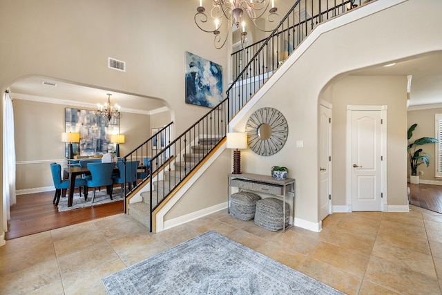 tiled foyer entrance with an inviting chandelier, ornamental molding, and a high ceiling