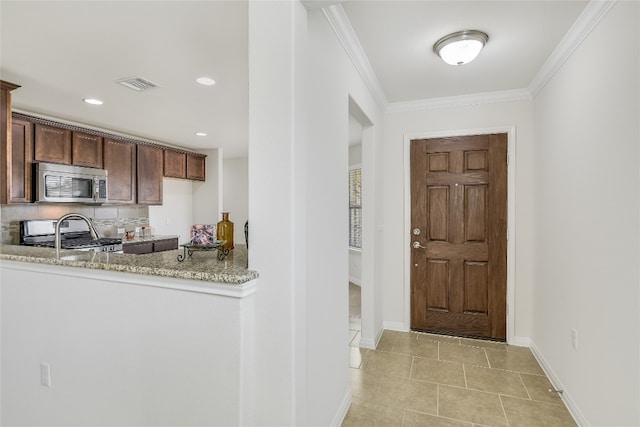 kitchen with light stone counters, crown molding, dark brown cabinets, appliances with stainless steel finishes, and backsplash