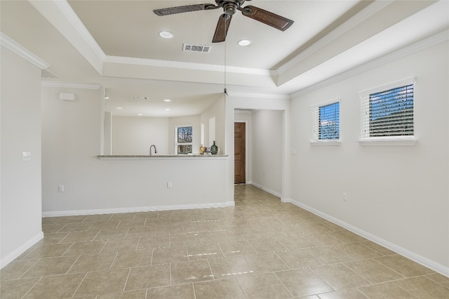 unfurnished living room with ornamental molding, light tile patterned floors, ceiling fan, and a tray ceiling