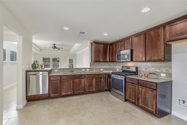 kitchen featuring light stone counters, sink, backsplash, and appliances with stainless steel finishes