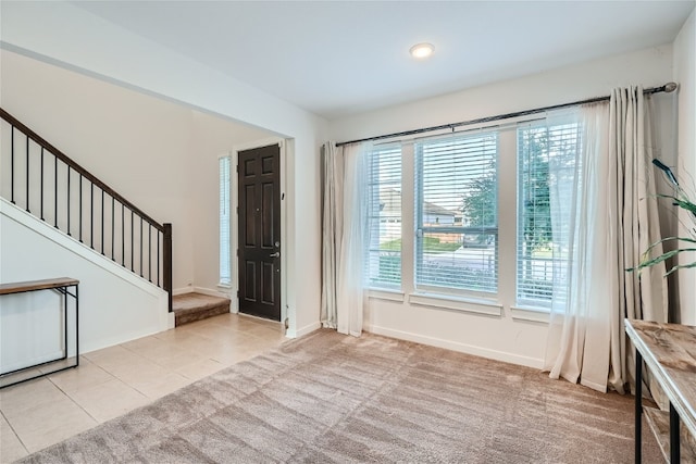 carpeted foyer entrance with a wealth of natural light