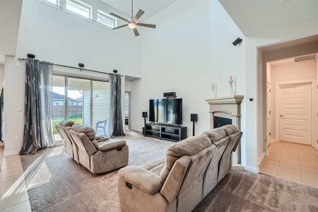 tiled living room with ceiling fan and a high ceiling