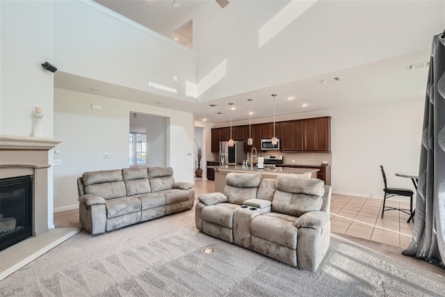 tiled living room featuring sink, ceiling fan, and a towering ceiling