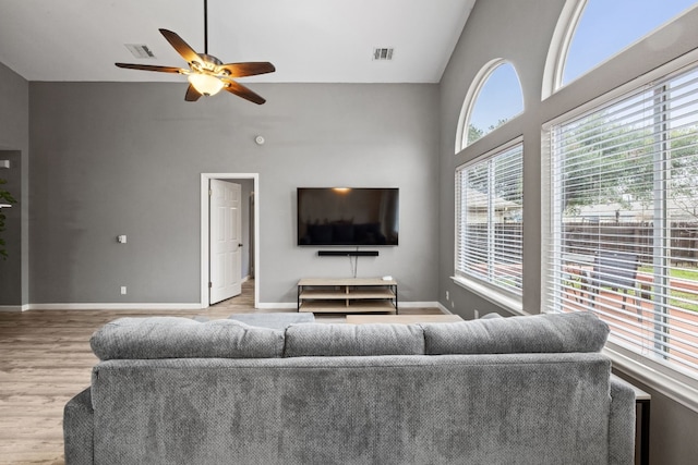 living room with ceiling fan, high vaulted ceiling, and light hardwood / wood-style floors