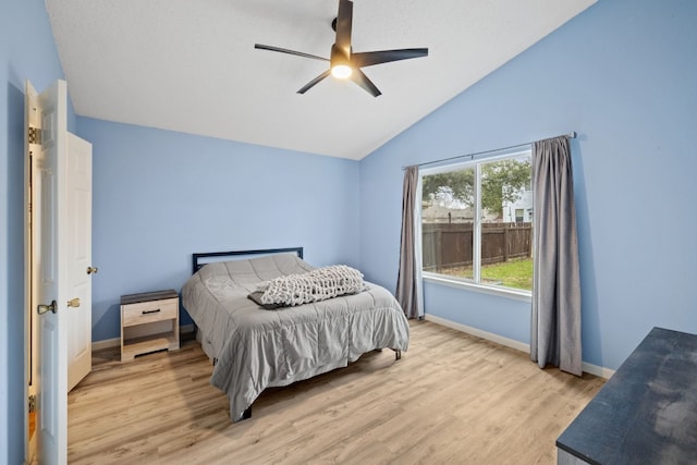 bedroom with ceiling fan, lofted ceiling, and light wood-type flooring