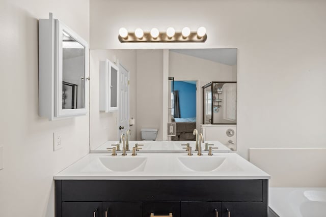 bathroom featuring vanity, a bath, and toilet