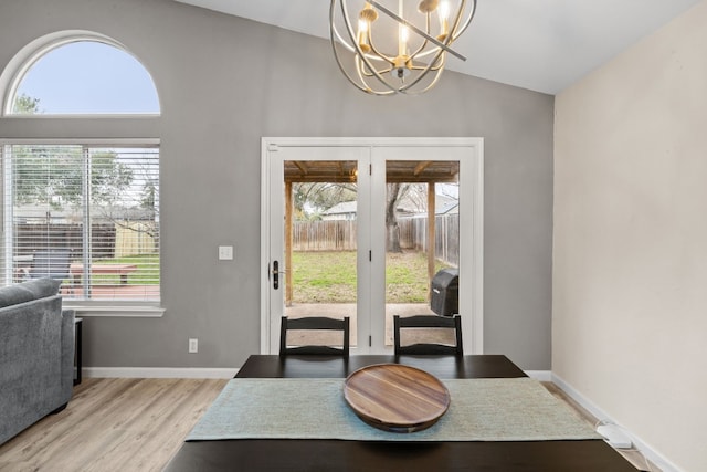 dining room with french doors, lofted ceiling, a chandelier, and light hardwood / wood-style floors