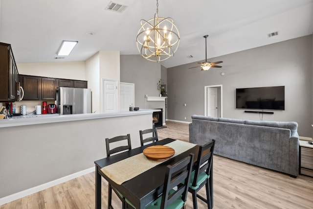 dining space with lofted ceiling, ceiling fan with notable chandelier, and light hardwood / wood-style floors