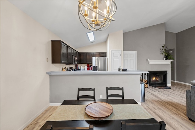 dining area with a notable chandelier, light hardwood / wood-style flooring, and vaulted ceiling