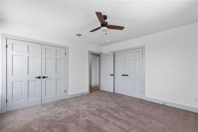 unfurnished bedroom featuring multiple closets, ceiling fan, and carpet