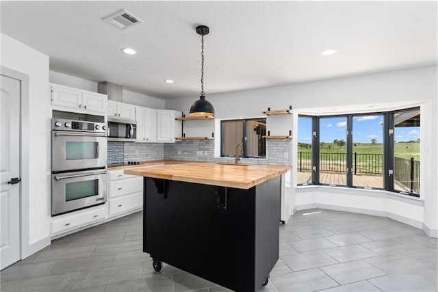 185 Eely Rd, Mcdade, TX 78650 - kitchen with white cabinetry, open shelves, butcher block countertops, visible vents, and appliances with stainless steel finishes