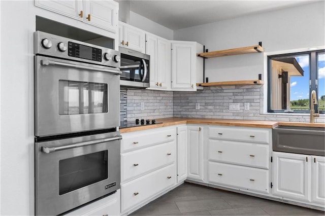 kitchen featuring sink, stainless steel appliances, white cabinets, wood counters, and decorative backsplash