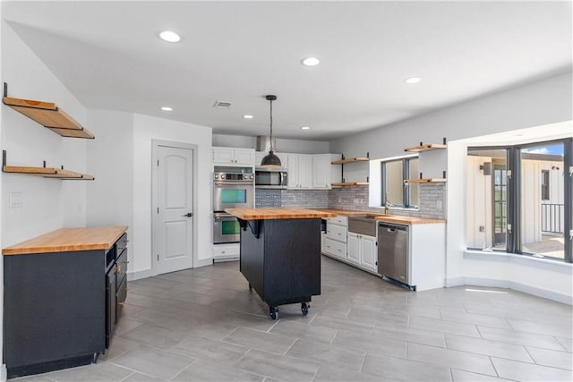 kitchen featuring white cabinetry, a center island, and butcher block countertops