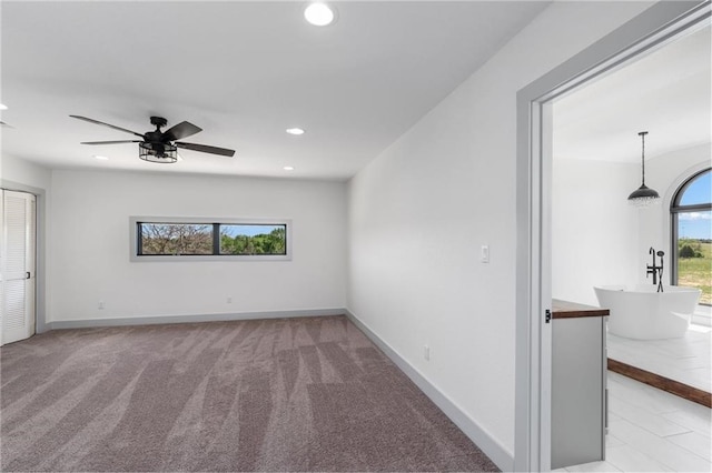 spare room featuring ceiling fan and light colored carpet