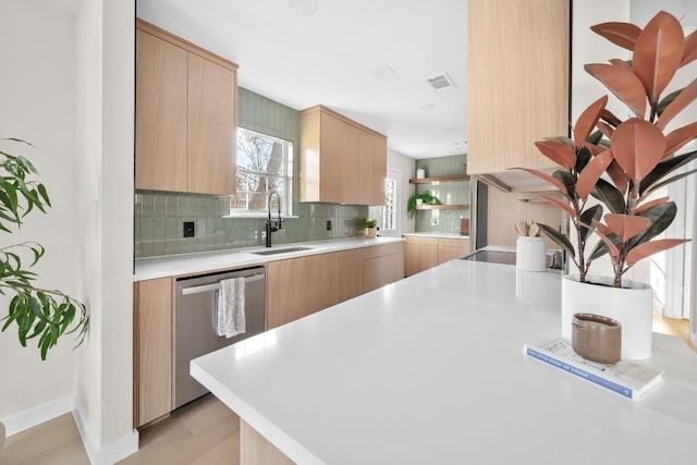 kitchen with sink, backsplash, stainless steel dishwasher, light brown cabinets, and light wood-type flooring