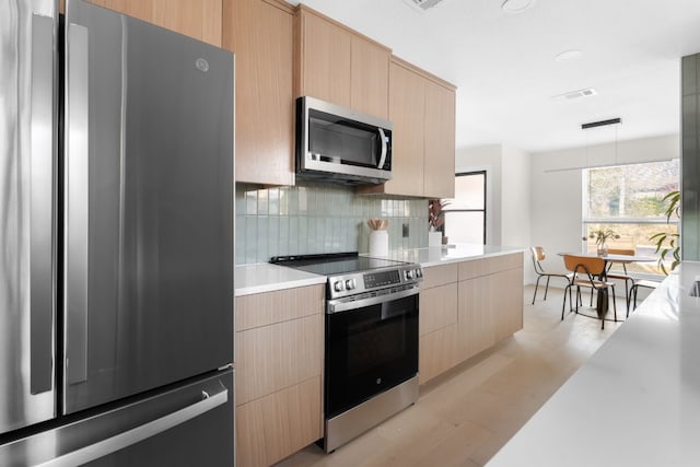 kitchen featuring hanging light fixtures, decorative backsplash, stainless steel appliances, and light brown cabinets