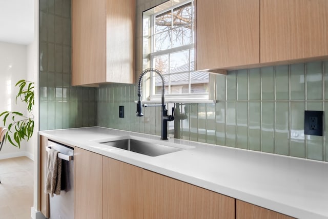 kitchen featuring tasteful backsplash, sink, stainless steel dishwasher, and light brown cabinetry