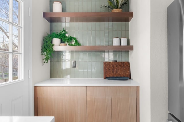 room details featuring tasteful backsplash and fridge