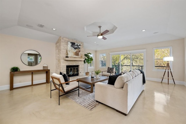 living room with a tray ceiling, vaulted ceiling, a large fireplace, and ceiling fan