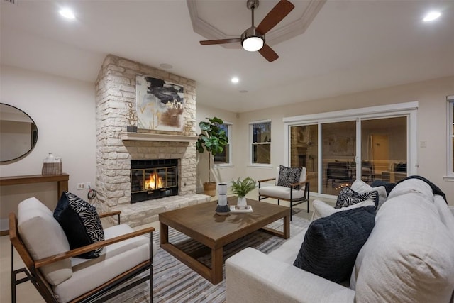 living room with a stone fireplace and ceiling fan