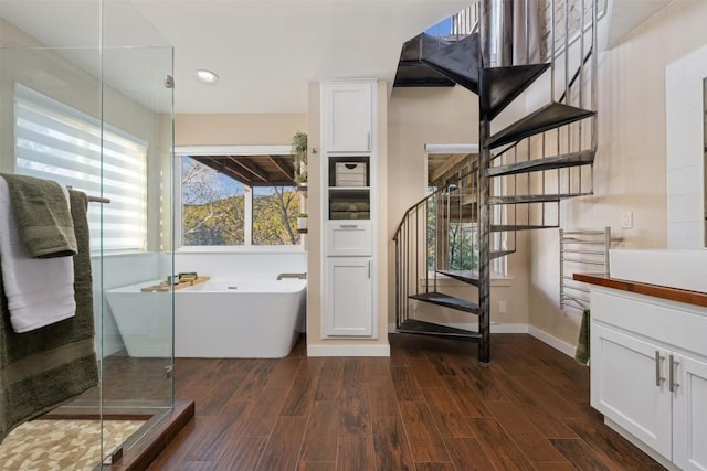 bathroom with hardwood / wood-style flooring, vanity, and plus walk in shower