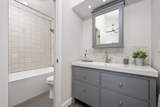 full bathroom featuring tiled shower / bath, tasteful backsplash, vanity, ceiling fan, and toilet