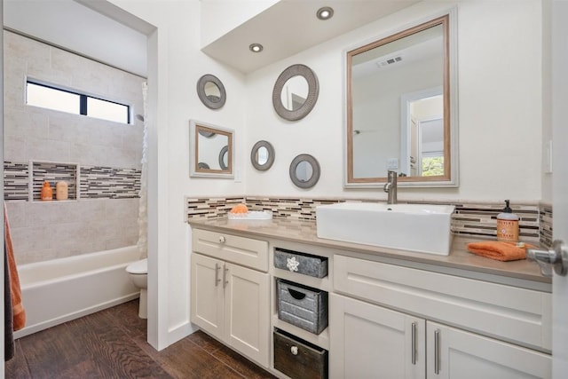 full bathroom with toilet, vanity, shower / bath combo with shower curtain, hardwood / wood-style floors, and backsplash