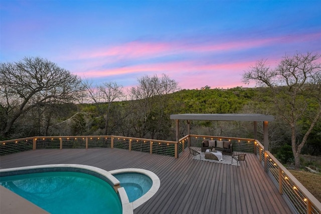 pool at dusk with an outdoor living space, a wooden deck, and an in ground hot tub