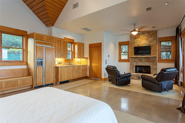 bedroom with sink, a fireplace, high vaulted ceiling, and paneled built in refrigerator