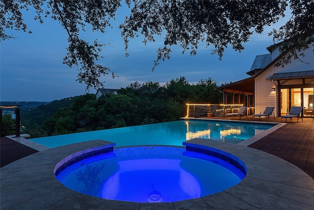 pool at dusk with an in ground hot tub