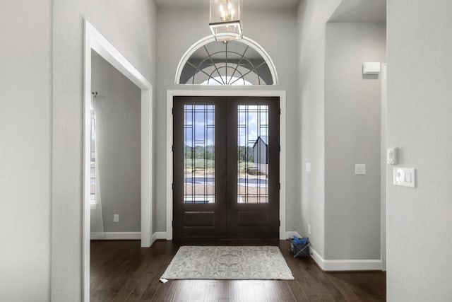 entryway with an inviting chandelier, dark wood-type flooring, and french doors