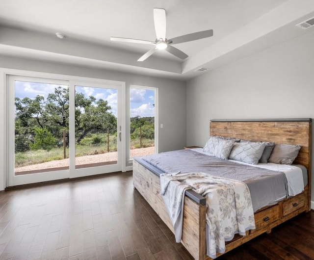 bedroom featuring access to exterior, a tray ceiling, dark hardwood / wood-style floors, and ceiling fan