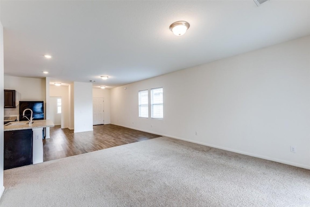 unfurnished living room featuring sink and dark carpet