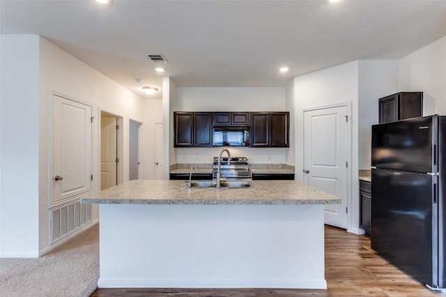 kitchen featuring sink, light hardwood / wood-style flooring, dark brown cabinets, black appliances, and an island with sink