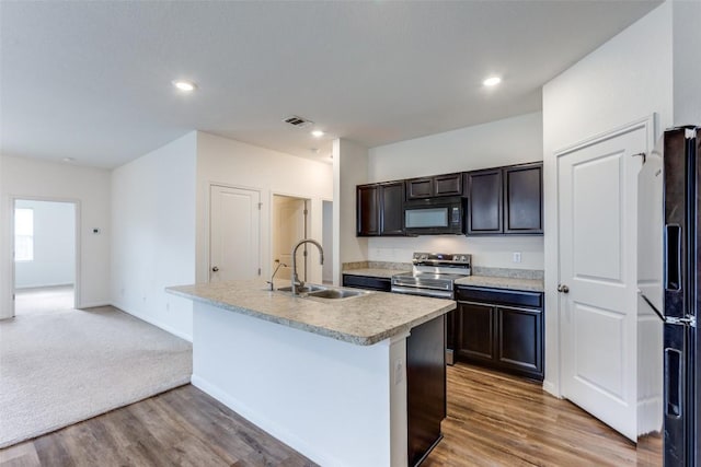 kitchen with sink, hardwood / wood-style flooring, a kitchen island with sink, black appliances, and dark brown cabinets