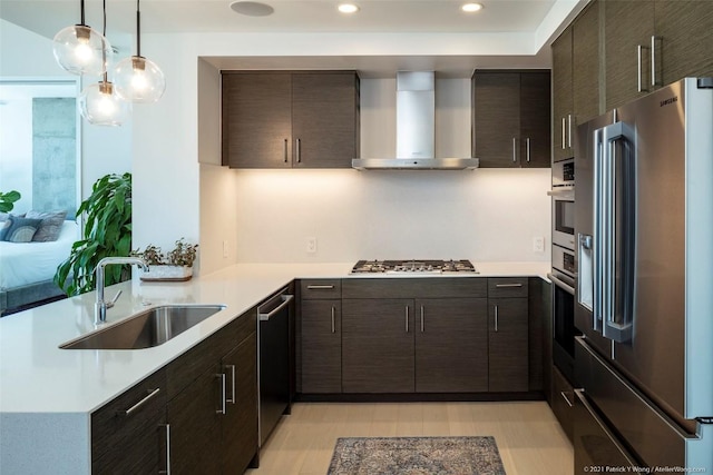 kitchen featuring wall chimney exhaust hood, sink, kitchen peninsula, pendant lighting, and stainless steel appliances