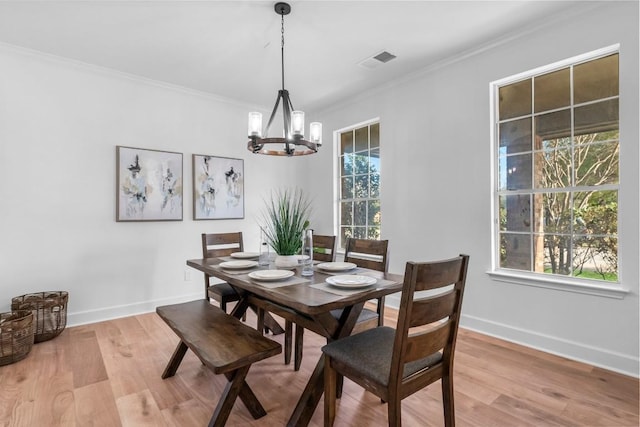 dining space with ornamental molding, a chandelier, light hardwood / wood-style flooring, and plenty of natural light