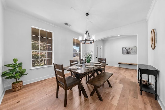 dining space featuring crown molding, an inviting chandelier, and light hardwood / wood-style floors