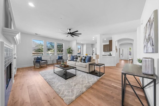 living room featuring ceiling fan, sink, and light hardwood / wood-style flooring