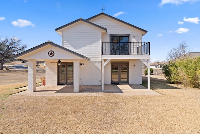 back of property featuring a patio area, a balcony, ceiling fan, and a lawn