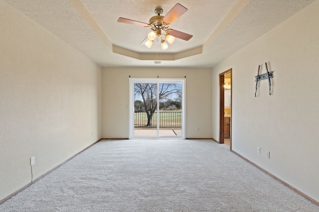 carpeted spare room with ceiling fan, a raised ceiling, and a textured ceiling