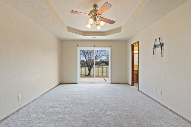 1210 Sun Ray, Horseshoe Bay, TX 78657 - spare room with light carpet, a ceiling fan, a tray ceiling, a textured ceiling, and a textured wall