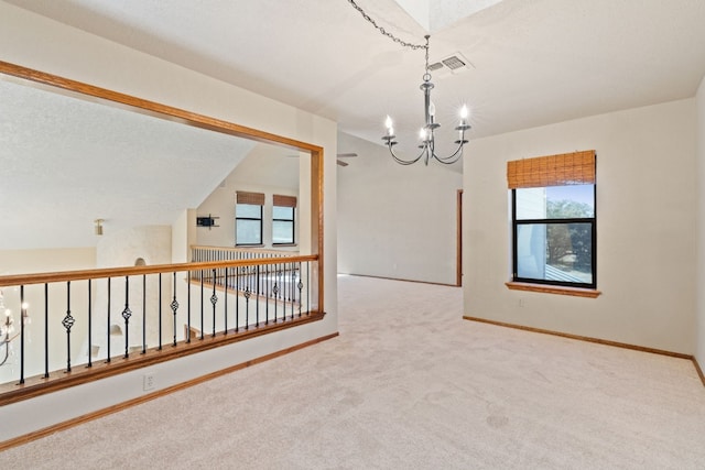 spare room featuring carpet floors and a chandelier