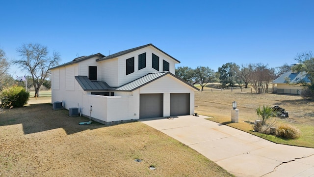 view of front of house with central AC, a garage, and a front lawn