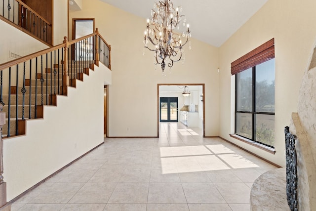 tiled foyer entrance featuring a chandelier and high vaulted ceiling