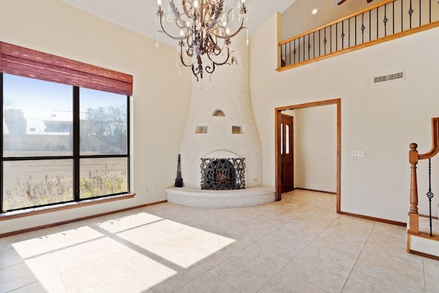 tiled living room with an inviting chandelier, a large fireplace, and a high ceiling