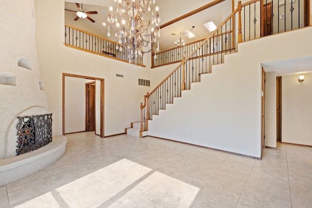 living room featuring a towering ceiling and ceiling fan with notable chandelier