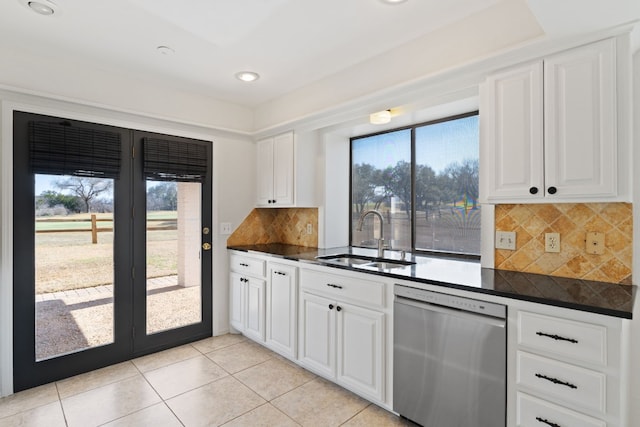 kitchen with sink, light tile patterned floors, stainless steel dishwasher, and white cabinets