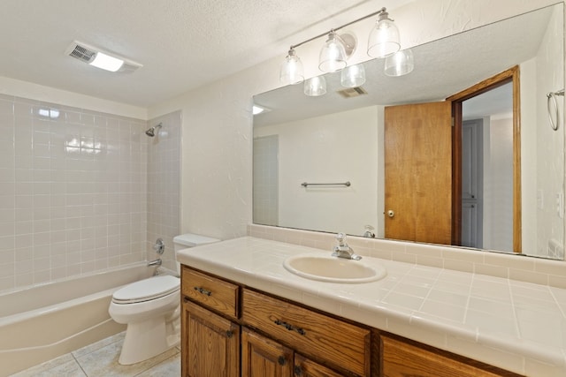 full bathroom featuring tiled shower / bath combo, vanity, toilet, tile patterned floors, and a textured ceiling